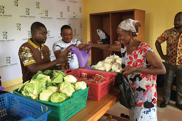 Two men hand a woman food at a food pantry