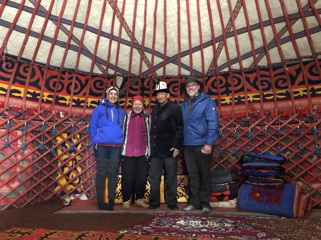 Four adults stand inside a large traditional dwelling in Kyrgyzstan.