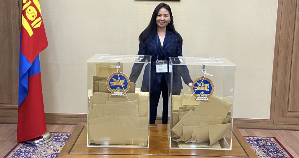 A woman stands behind two ballot boxes at the Mongolian Embassy in Seoul.