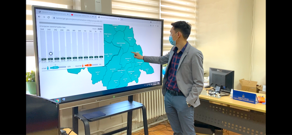 A man points at a large touch screen showing a map of Mongolia's voting districts.