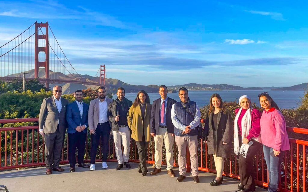 Ten people standing on a balcony with the Golden Gate Bridge behind them.