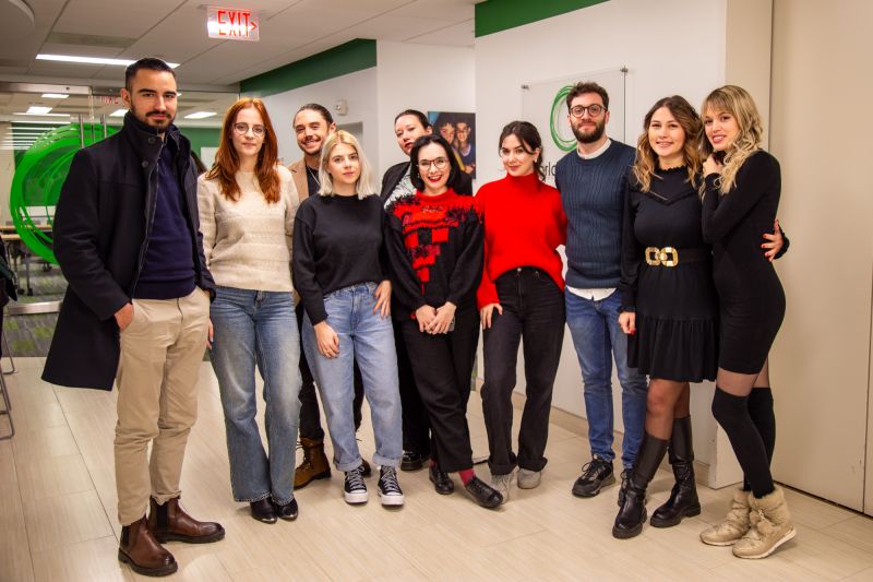 A group of young adults pose together in an office setting.