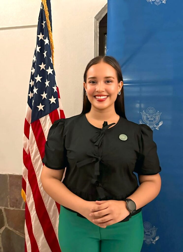 Global UGRAD student poses in front of an American flag on a standing pole.