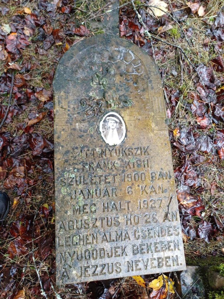 A gravestone with Hungarian language etched in it and a marble white picture of a man's head at the top.
